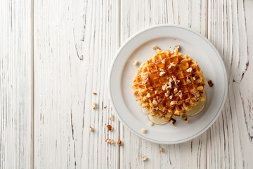 Fototapeta na wymiar Belgian waffles with honey and walnuts on white wooden background.