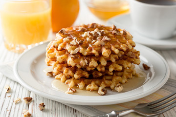 Belgian waffles with honey and walnuts on white wooden background.