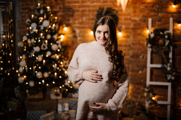 Beautiful pregnant woman with long hair against the Christmas tree