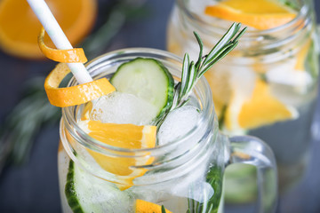Homemade orange lemonade with cucumber and rosemary on the dark rustic background