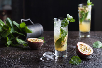 Cold mojito with passion fruit, mint and ice on the black background