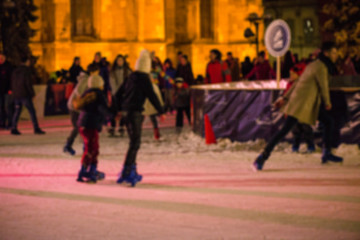 Abstract blurry background of ice skating people in city center during Christmas market.