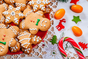 Obraz na płótnie Canvas Christmas gingerbread cookies homemade on red plate with branches of Christmas tree and decor on home New Year table. Merry Christmas postcard