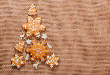 Fototapeta na wymiar Christmas tree made of gingerbread cookies homemade and New Year decor on burlap backgraund. Merry Christmas postcard. Free space