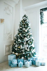 Christmas living room with a Christmas tree, gifts and a large window. Beautiful New Year decorated classic home interior