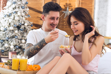 Beautiful couple in love feeds each other. Healthy Eating. Healthy breakfast in bed. Couple celebrating Christmas together.