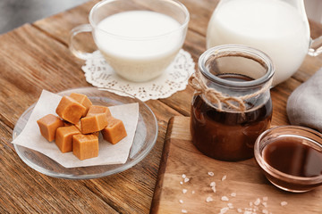 Composition with tasty candies and caramel sauce on table