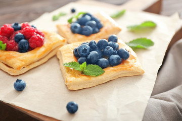 Tasty pastries with berries on board, closeup
