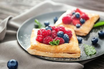Plate with tasty berry pastries on table