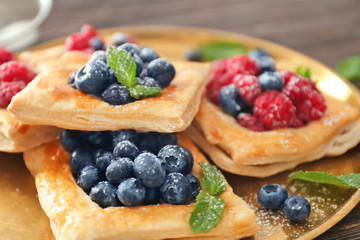 Tasty pastries with berries on tray, closeup