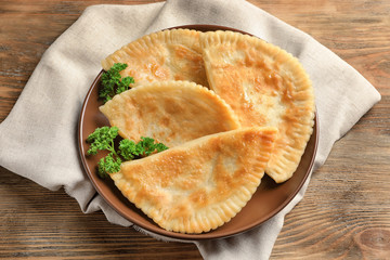 Plate with deep fried samosas on wooden background