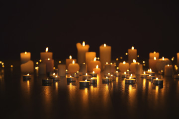 Burning candles on floor in darkness - obrazy, fototapety, plakaty
