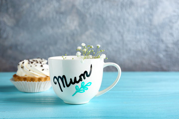 Obraz na płótnie Canvas Cup with word MUM and dessert for Mother's day on table