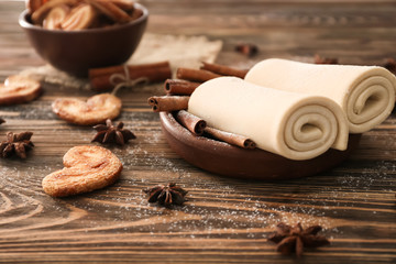 Plate with rolled flaky dough on wooden table