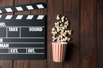 Clapperboard and popcorn on wooden background
