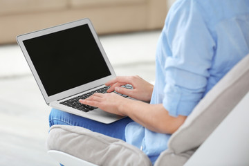 Young woman using laptop at home, closeup