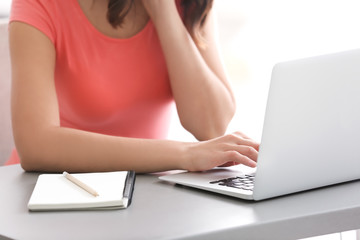 Fototapeta premium Young woman using laptop while sitting at table, closeup