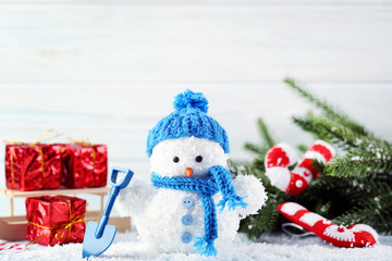 Small snowman toy with gift boxes and fir-tree branches