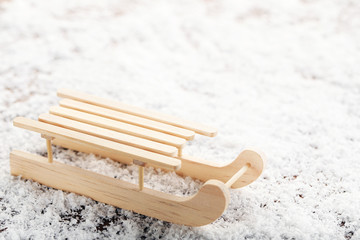 Wooden toy sleigh on white snow