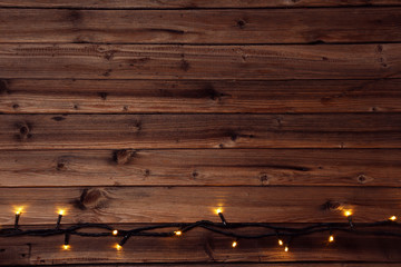 Fototapeta na wymiar Christmas garland lights on brown wooden table