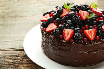 Chocolate cake with berries in plate on wooden table