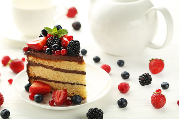 Piece of chocolate cake with berries in plate on wooden table