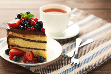 Piece of chocolate cake with berries in plate on wooden table