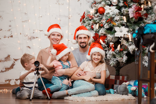 Image of parents, two daughters in caps of Santa and son with telescope