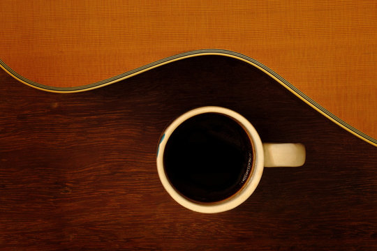 cup of coffee and acoustic guitar on wooden floor