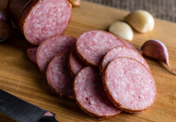 Slices of sausage and garlic lie cutting board