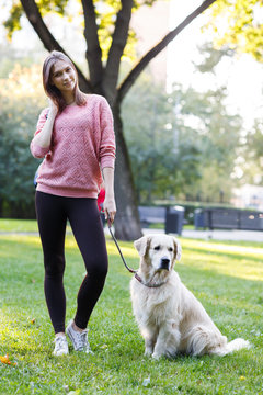 Photo of brunette holding leash of labrador on lawn