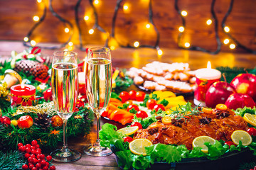 Christmas table dinner time with roasted meats decorated in Christmas style with glasses champagne. Background thanksgiving. The concept of a family holiday, delicious food.