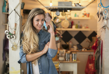 Beautiful young woman in a hipster kitchen talks to her phone dressed in a jeans and a white shirt