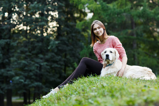 Image from below of girl sitting with dog on green lawn