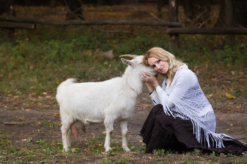 Blonde woman stroking goats on a green glade