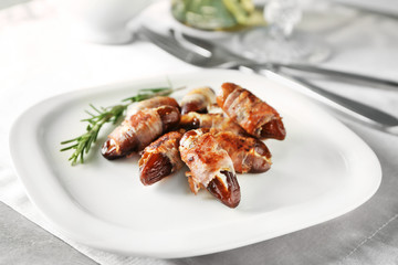 Plate with bacon wrapped dates on table