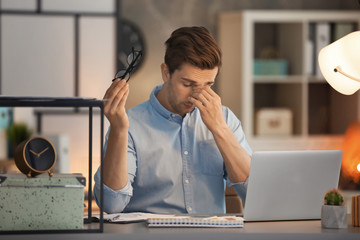 Tired young man working in office at night
