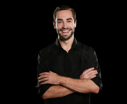 Young handsome man smiling on black background