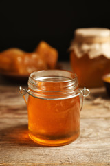Glass jar with honey on wooden table