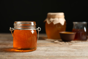 Glass jar with honey on wooden table