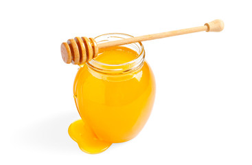 Glass jar with honey and dipper on white background