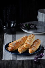 On a wooden table on a plate a bunch of sausages in a dough