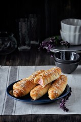 On a wooden table on a plate a bunch of sausages in a dough
