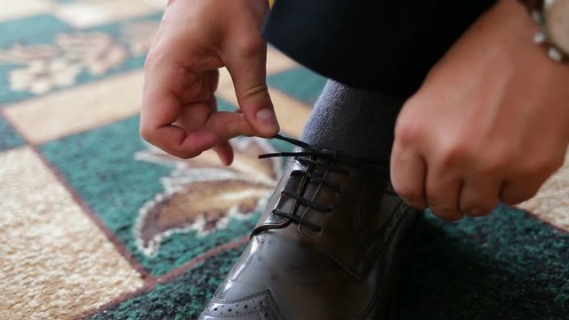 groom putting his wedding shoes. Hands of wedding groom getting ready in suit