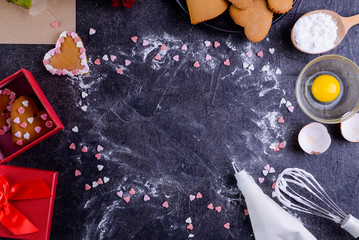 Black stone background with frame of homemade cookies in shape of heart, flower, food ingredients and decor. gift for lover on Valentine's day. Love concept. Selective focus. Space for text