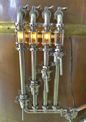 Pipes and lights on copper container in microbrewery.