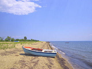 White boat on the beach by the beautiful blue sea on sunny day.
