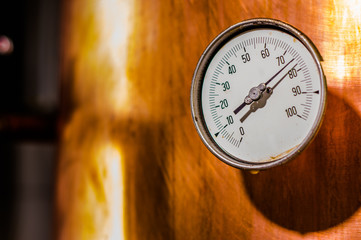 Close up of a pressure gauge inside of a modern beer plant brewery with vessels, tubs and pipes...