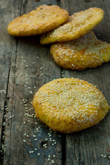 A few round cheese cakes with sesame seeds on a wooden background.