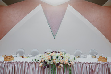 Minimalistic wedding table for the bride and groom. Decorated with roses.